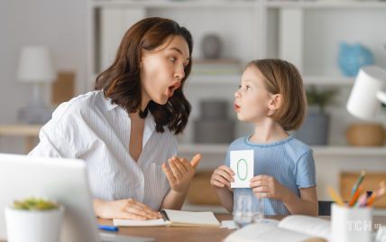 Mujer adulta y niña practicando la pronunciación con una tarjeta de número cero.