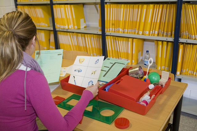 Terapeuta ocupacional o educadora organizando materiales educativos y fichas para una sesión de aprendizaje o terapia.