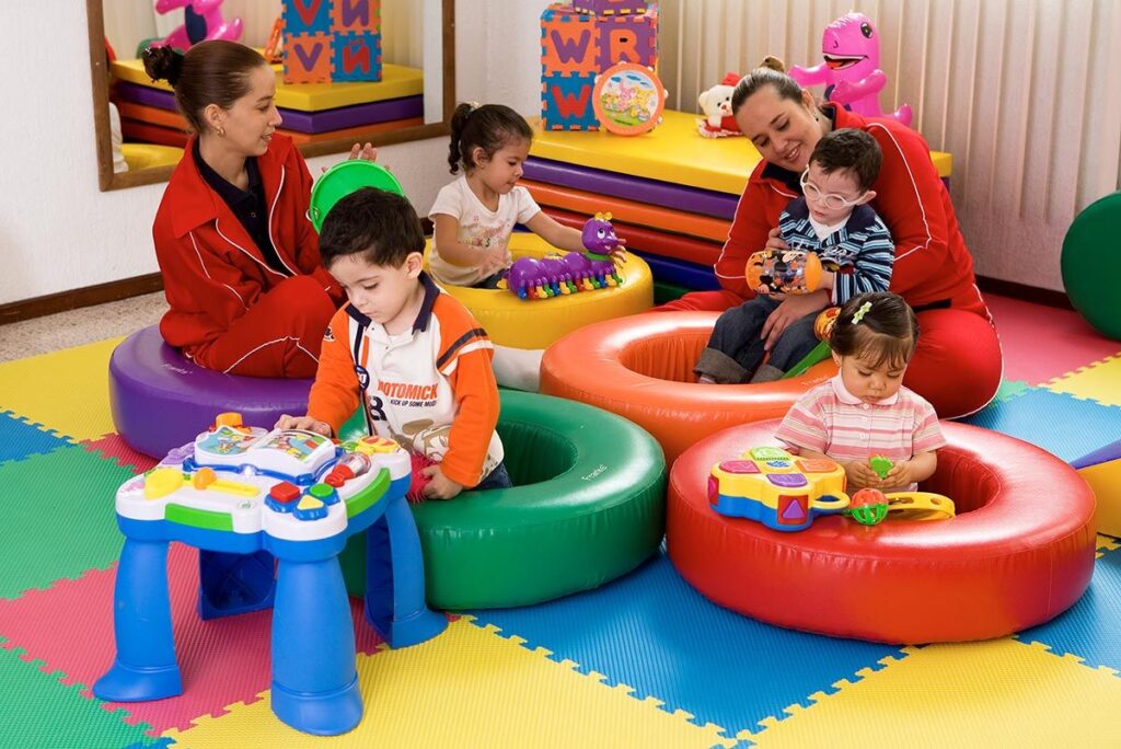 Niños participando en actividades de estimulación temprana junto a terapeutas infantiles en un centro especializado.